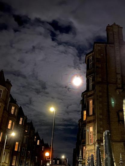 Colorful moonbow through thick clouds in between terraced flats
