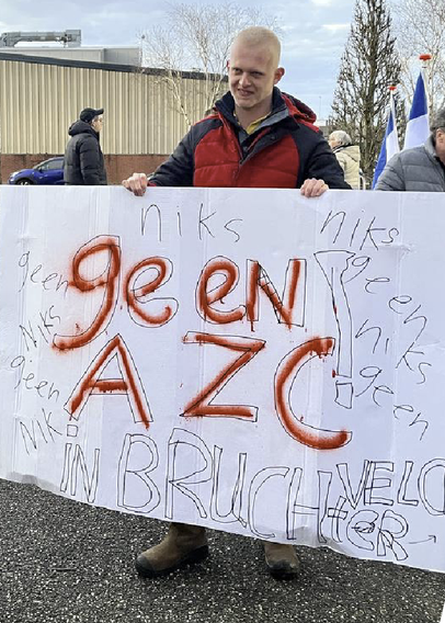 Een man staat met een zelfgemaakt bord te protesteren tegen de komst van een AZC in het dorp Bruchterveld.