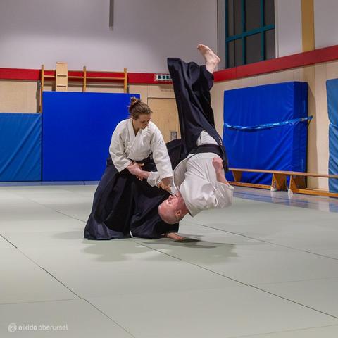 Female aikidoka throwing a male attacker in free fall