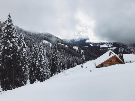 The roof of a mountain hut and snow all around with dark clouds in sky