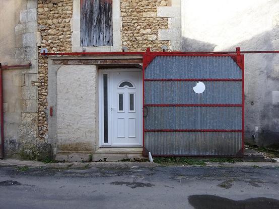 porte de maison en pvc derrière une porte de garage en tôle