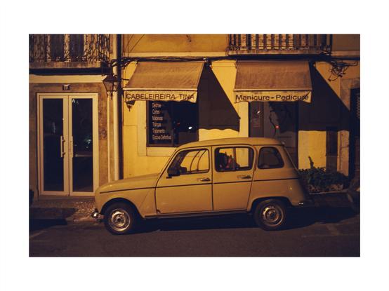 an old car at night in front of a manicure salon in lisbon, set in sepia colored tones