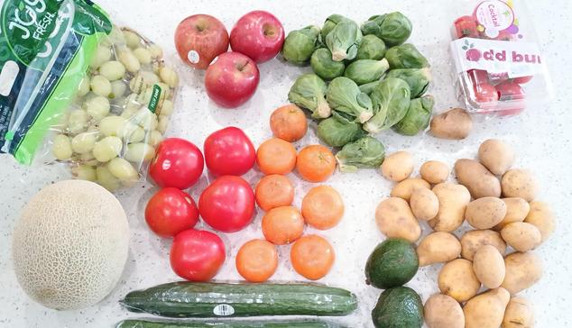 A spread of veggies and fruit. Shown are grapes, apples, Brussels sprouts, small tomatoes, large tomatoes, cantaloupe, cucumbers, avocados and potatoes.