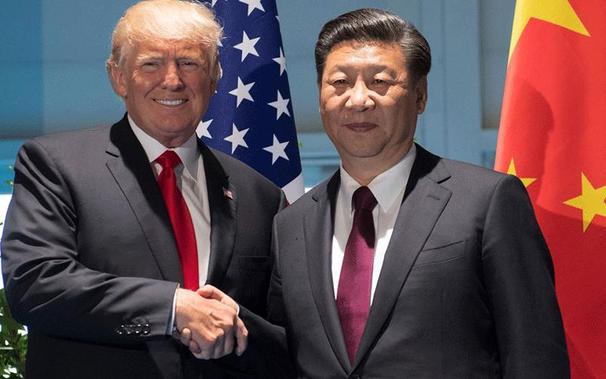Two individuals in formal suits are shaking hands, positioned against the backdrop of two large flags—one representing the United States and the other representing China. The scene suggests diplomacy or formal agreement.