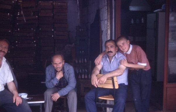 Un groupe d'homme et un enfant prenant la pose devant une boutique
