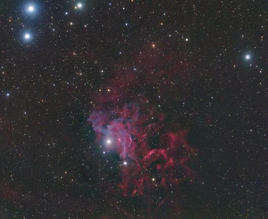 Flaming Star Nebula:
Background is grey/black with stars dotted throughout.

Filling much of the center area of the image is red nebulosity,. There are undulations of brighter and fainter areas of red nebulosity including some dark areas with no nebulosity.

At the core center of the image are some ribbon streams of light purple/blue nebulosity. These seem to originate from a particularly bright star at the center of the image (AE Auriga).