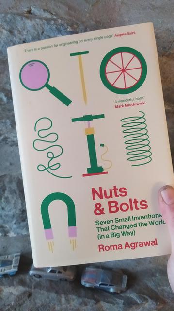 Photo of a hardback book. Titled "Nuts and Bolts, Seven  Small Inventions That Changed the World". Written by Roma Agrawal. 