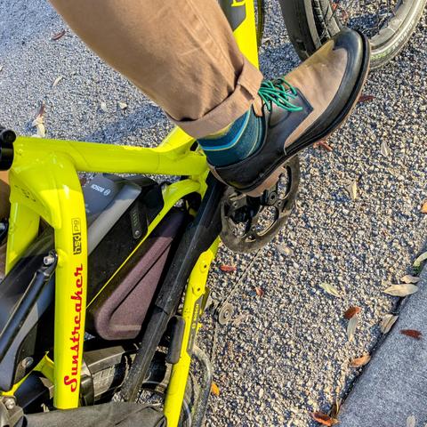 A photo of my right foot on the pedal of a 

yellow Tern HSD cargo bike with its name, Sunstreaker, in red on the seat stay

I'm wearing

tan and black wingtip derbies under a dark khaki pantleg, a bit of green striped sock showing.