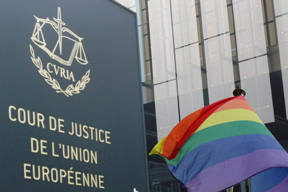 un drapeau aux couleurs de l'arc en ciel flottant à côté d'un panneau portant la mention "cour de justice de l'union européenne" 
