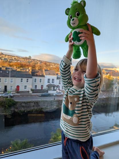 Patrick's son Patrick holds up a Good Luck Bear stuffed animal, with Cork, Ireland in the background.