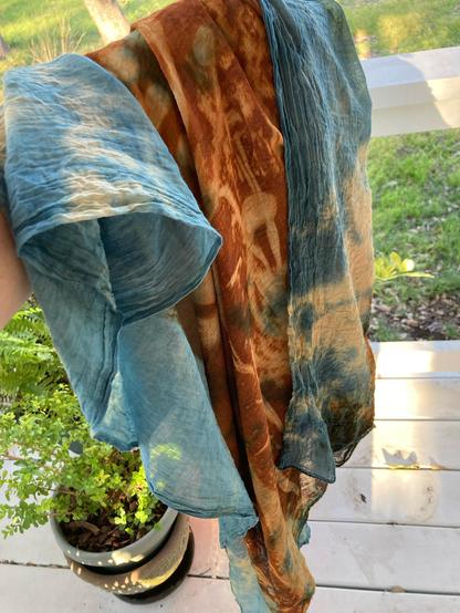 A blue and rust colored shawl bunch up an a hand.