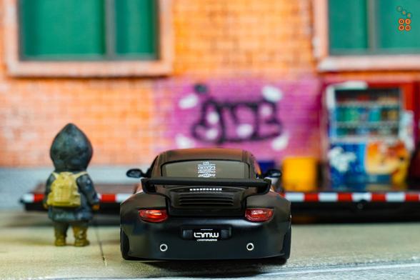 A rear side of Old & New 997, Matte Black by Tarmac Works in 1:64 scale with 1:64 figure on AREA 164