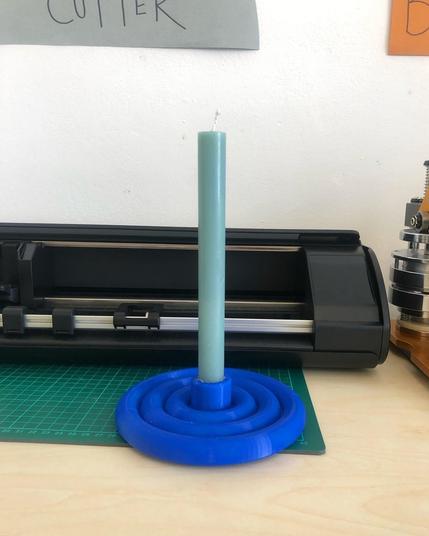 A pale blue candle held in a circular holder with a ribbed tubelike design. 