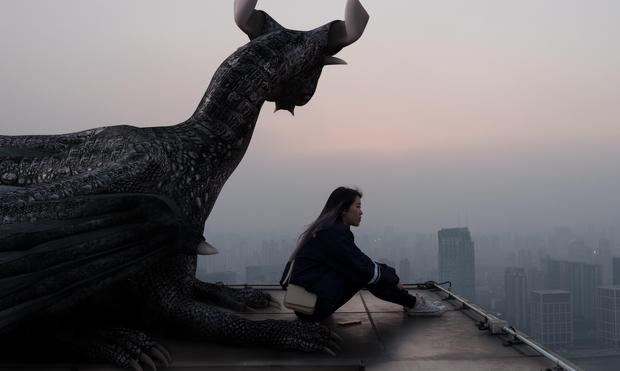 A woman and a dragon on a roof looking out at a hazy horizon.