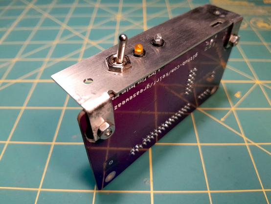 The GreaseWeazle itself is a small purple circuit board. Here it is mountd to a bracket of my design. It is made of brushed stainless steel, and features two 'legs' to mount the circuit board, two more holes to mount the bracket to the case, as well as a few other features: An opening for the GreaseWeazle's USB-C port, a large toggle switch to enable and disable write protection, a power LED, and an activity LED.