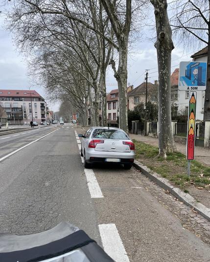Une Citroën C5 stationnée sur la bande cyclable en face de l’école Gustave Doré, route de Mittelhausbergen. La chaussée est déserte.