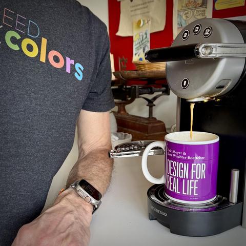 Pouring a large coffee in my A Book Apart Mug #18 “Designing for Resa Life” wearing my Six Colors t-shirt “I bleed Colors”