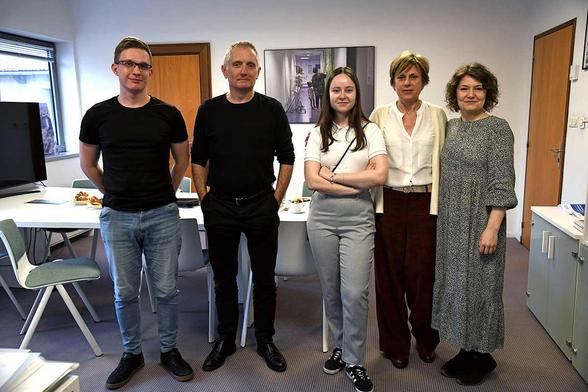 Cinq personnes debout, posant pour une photo de groupe dans une salle de réunion de l’AP-HM, avec une table et des dossiers en arrière-plan.
