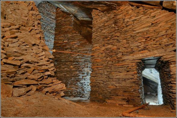 Une chambre d'exploitation souterraine dans une carrière d'ardoise.
Des confortations en pierres sèches maintiennnent le ciel, donnant l'impression d'être dans les soubassements d'un château.