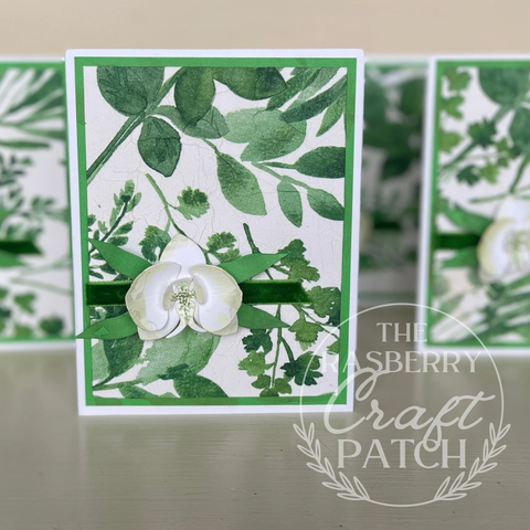 Handmade card front. Paper watercolours orchid, textured watercolour leaves background, simple green velvet ribbon strip