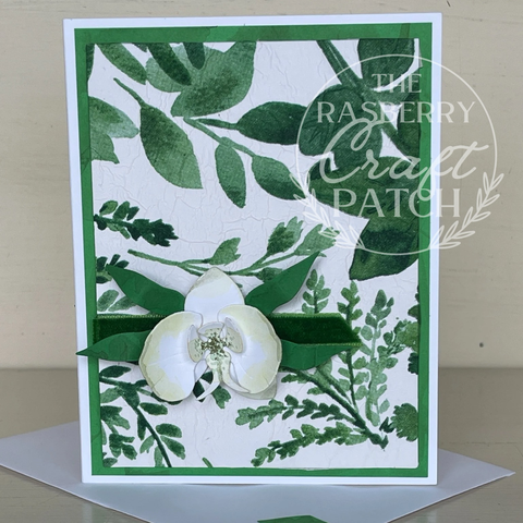 Handmade card front. Paper watercolours orchid, textured watercolour leaves background, simple green velvet ribbon strip
