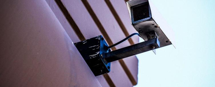 Security camera mounted on the side of a building, monitoring the surrounding area for safety and surveillance purposes