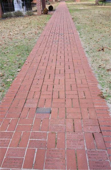 A photo of the completed pathway at the Hellen Keller Museum. It is a long, flat, straight path of red brick. 