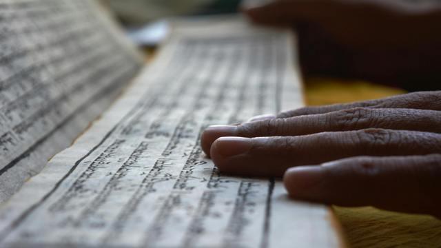 Hand on a Buddhist manuscript.