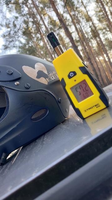 Ein Hygrometer und ein Helm auf einem Autodach.