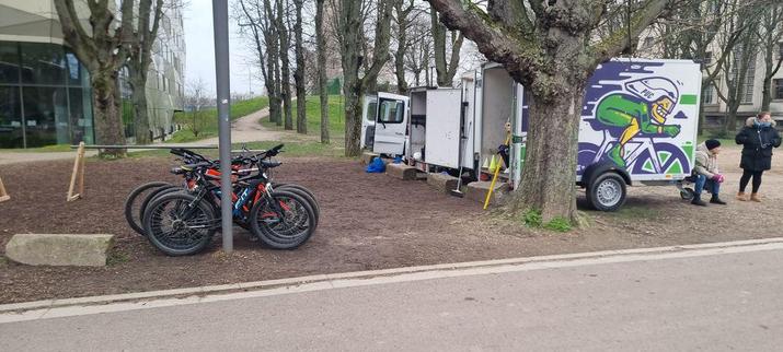 une place boisée ou est stationné un camion avec plusieurs vélos rangés à côté 
