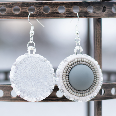 Grey flatstitch beaded earrings with matte grey cabochons, white and grey charlotte cut and Japanese beads, grey buckskin, and silver hooks