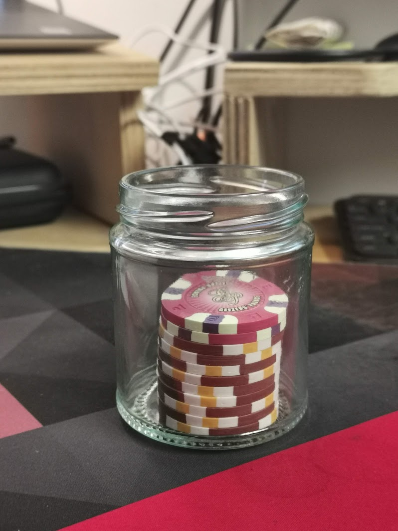 A small jar with purple and brown poker chips in it.