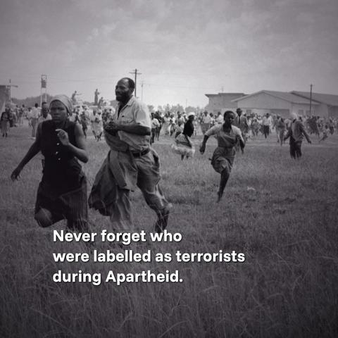 A photo of black South Africans running for their lives during the 1960 Sharpeville massacre, in which white police killed over 60 black protesters and injured hundreds more.

Over the photo, the following text is written: "Never forget who were labelled as terrorists during Apartheid."