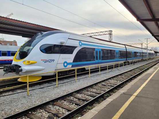 4-carriages EMU with blue lines and yellow front on a platform.