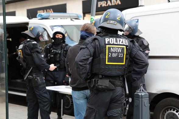 Auf einem Tisch liegen Nummern, 4 Beamte und eine Person aus der Blockade bei der erkennungsdienstlichen Behandlung.