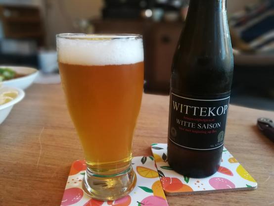 Ingeschonken bier, met ernaast een zwart flesje, waar met witte letters en rode accenten "Wittekop", "6.5" en "Witte saison" op staat