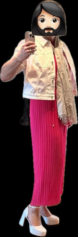Rita trägt einen plissierten pinken Hosenanzug mit einer weißen Jeansjacke, einem leichten Schal und weißen Plateau-Pumps