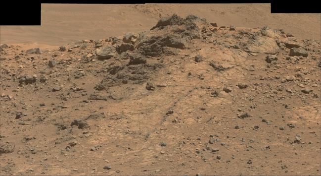 An ochre toned mosaic of a Martian landscape, capturing a lighter toned rock outcrop.