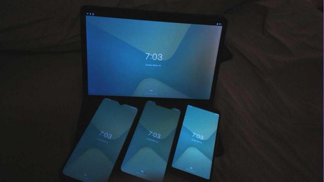 A picture taken with postmarketOS Edge, Snapshot 48, and cameractrl on my PinePhonePro.  In the photo are four of my other postmarketOS devices, all at the Phosh lockscreen.  In the back, my Xiaomi Pad 5 Pro (xiaomi-elish) with keyboard case.  In the front from left to right, OnePlus 6T (oneplus-fajita), Xiaomi Poco F1 (xuaomi-beryllium), and Pixel 3A (google-sargo).