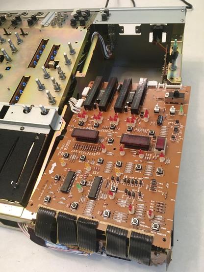The exposed control PCB and part of the frame of an Akai MG614 multitrack cassette recorder is visible due to the faceplate having been removed.