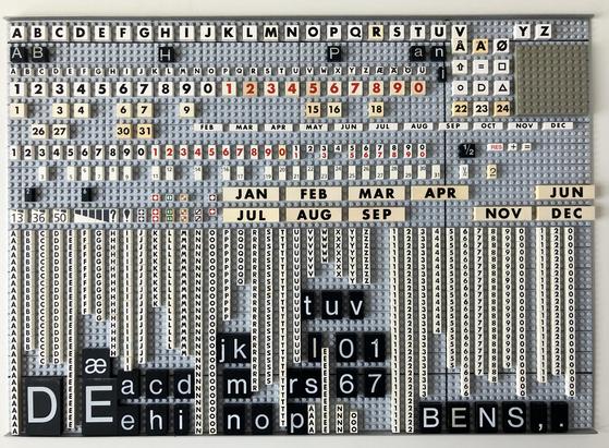 Letter tiles laid out on a smaller Modulex display board. There are several sizes of letters and numbers with the alphabet sets in various stages of completion. 