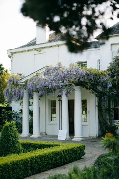 A white house adorned with vibrant purple flowers in the front garden, creating a charming and inviting atmosphere