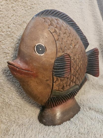 Vintage hand carved wooden fish that is looking at the camera.