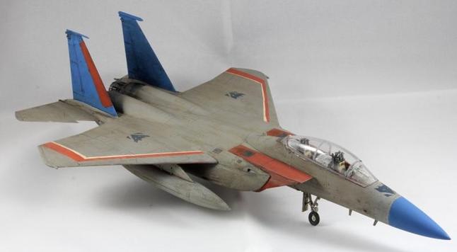 A 1:72 scale model of an F-15 E "Strike Eagle" painted in grey with blue and red highlights and purplish Decepticon roundels to make it look like Starscream from the Generation 1 Transformers. The background is a whiteish void.