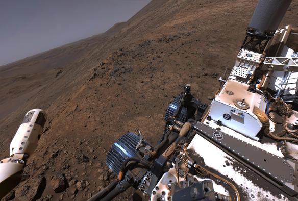A shot captured by Mars rover Perseverance with her right navigation camera. Percy stands on the steep slope of a rocky mound, itself sitting on the steep slopes of the rim of Jezero Crater.