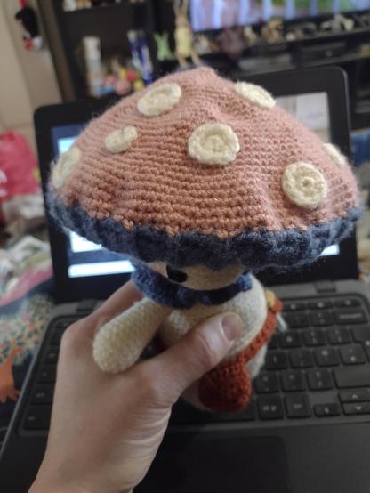 The top of the mushroom person's cap. It is a dusky pink with pale cream spots.