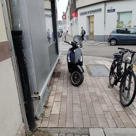 Un scooter sur le trottoir devant le coiffeur au coin de la rue de la Libération et de la route de Mittelhausbergen