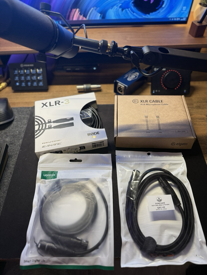 4 different xlr cables in their packaging laying in a desk with a microphone and audio interface visible in the background