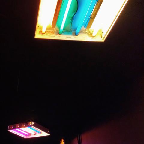 Des néons colorés éclairement un plafond d'un couloir sombre