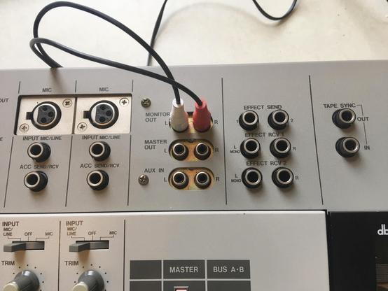 Close-up of some input and output jacks on the top rear of an Akai MG614 multitrack cassette recorder. Some RCA jacks are plugged into the Monitor Out jacks.